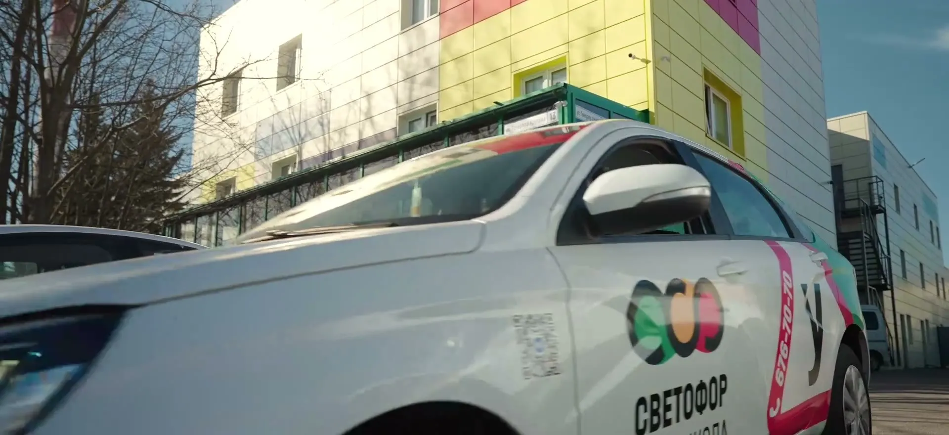 Кадр из фильма о компании: брендированный автомобиль автошколы «Светофор»